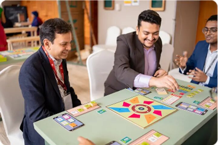 Participants and a mentor work through a board-game prototype together at FIF